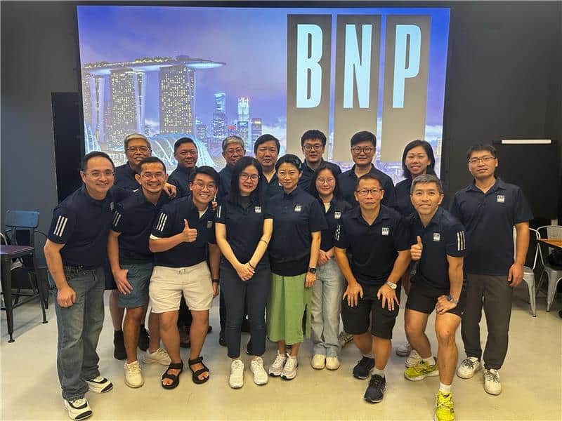 Group photo of a Singapore office team posing in front of a cityscape background.