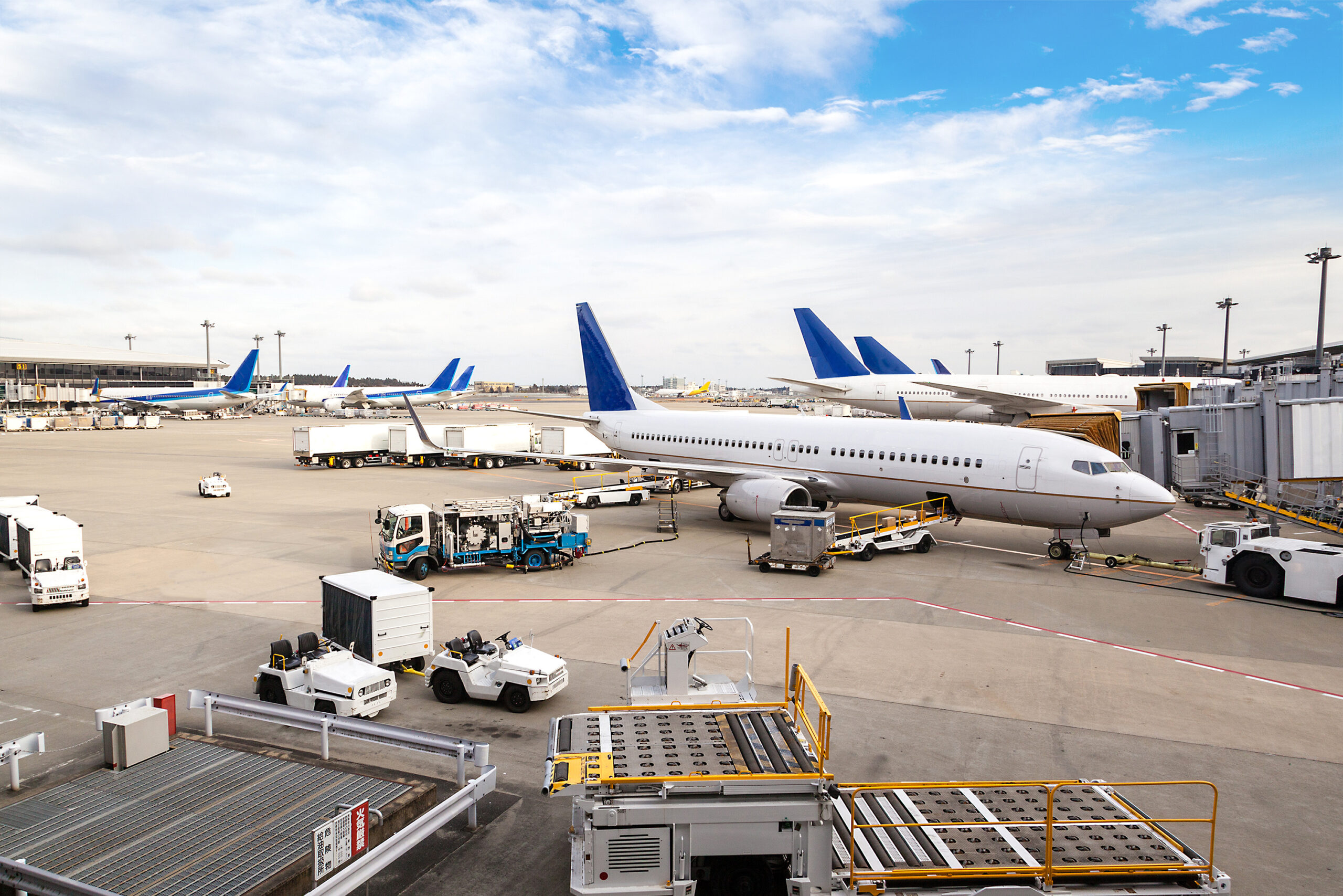 Airport terminal with various aircraft and ground handling equipment on the tarmac.