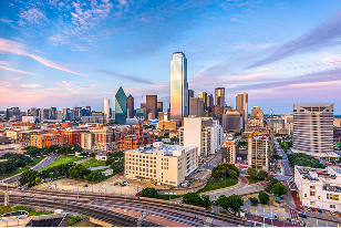 Sprawling skyline of downtown Dallas, Texas with modern skyscrapers, highways, and blue sky.