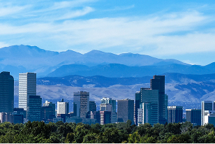 Expansive city skyline with modern high-rise buildings and distant snow-capped mountains.